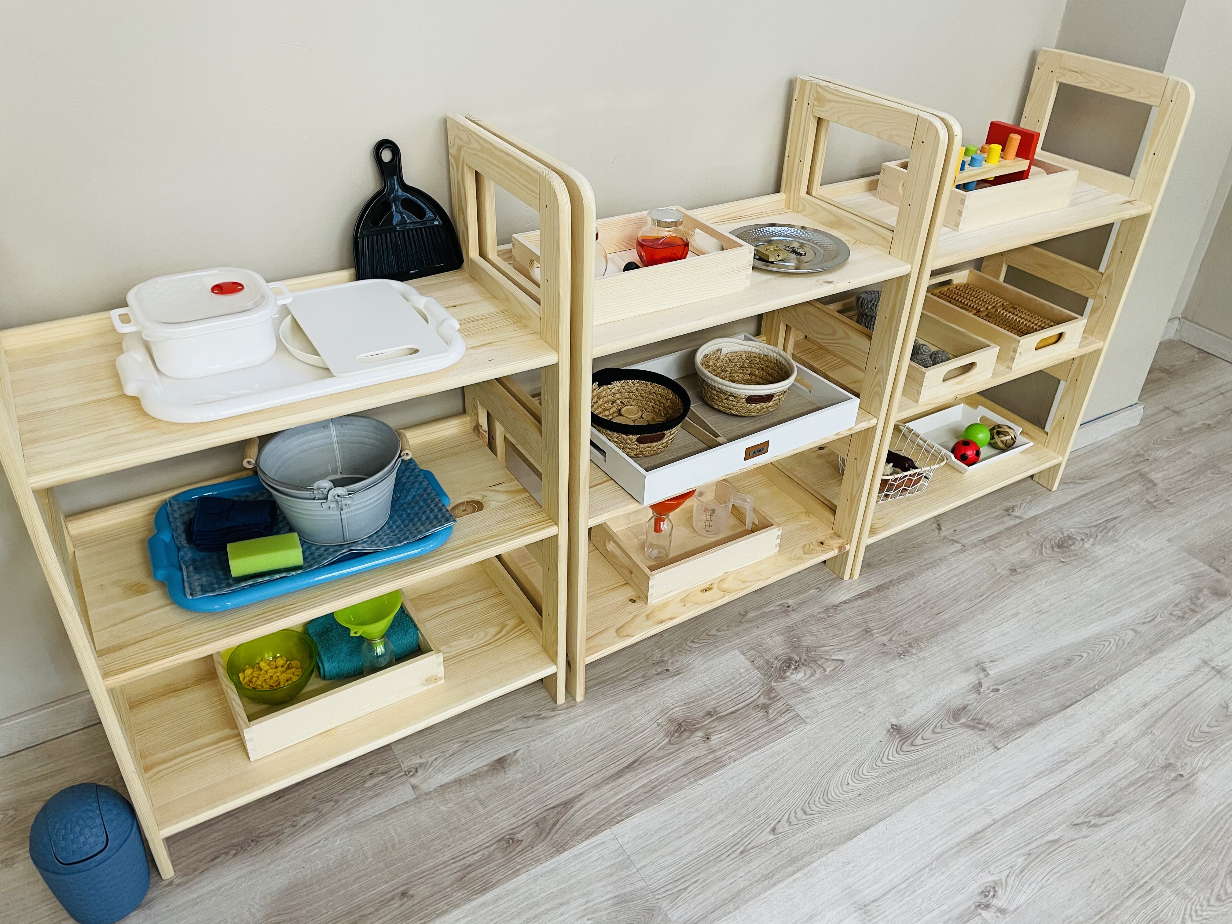 Regały Montessori z tacami do ćwiczeń praktycznych umiejętności w przedszkolu Jagódka